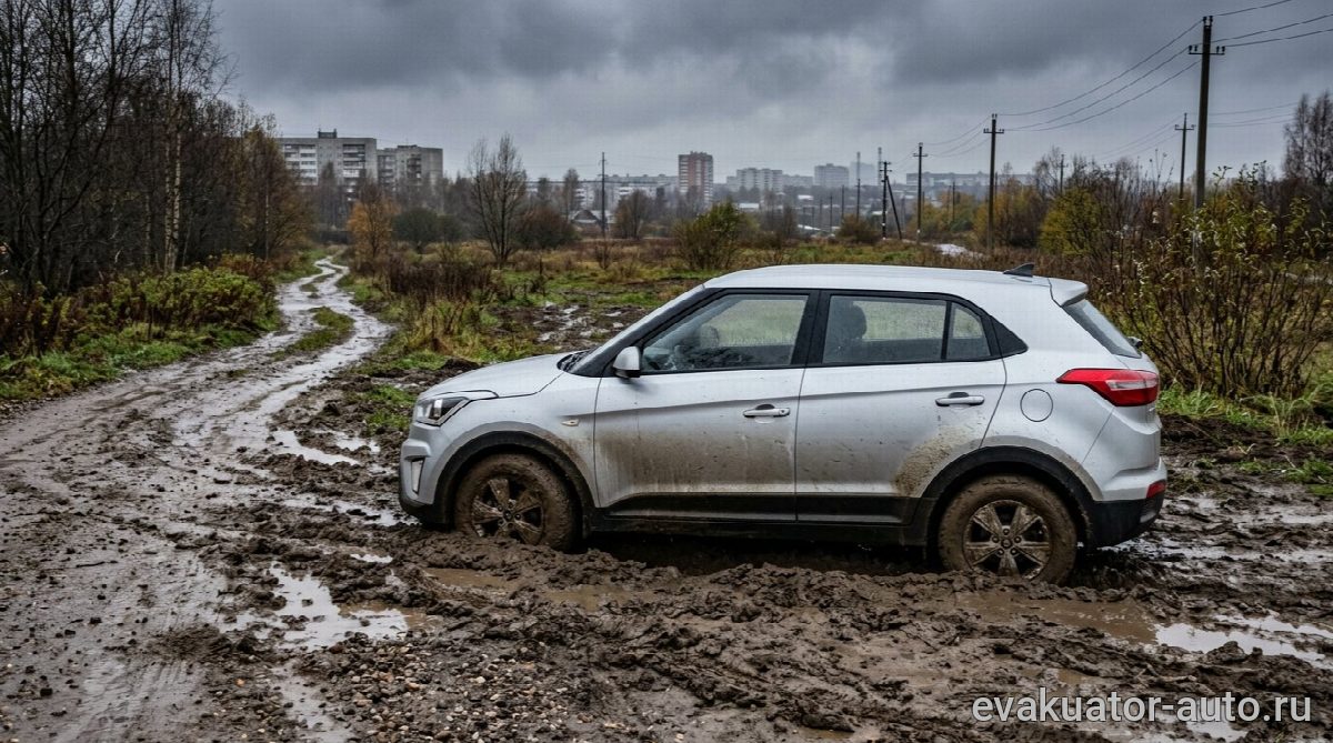 Легковой автомобиль, глубоко застрявший в грязи на грунтовой дороге после дождя